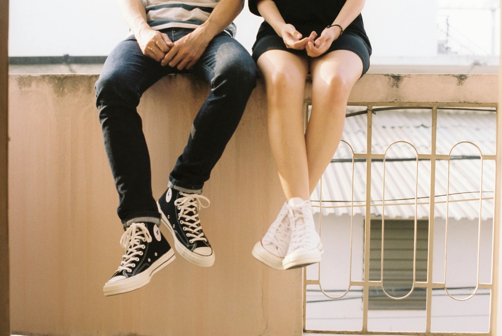 Couple seated next to each other with hands fidgeting in their laps and legs dangling